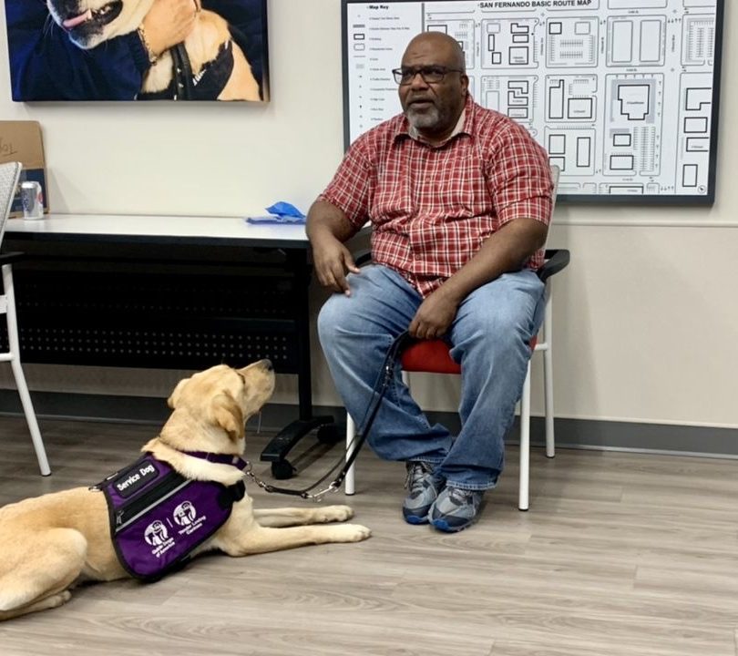 Donnell Nichols seated with his service dog, Bennett